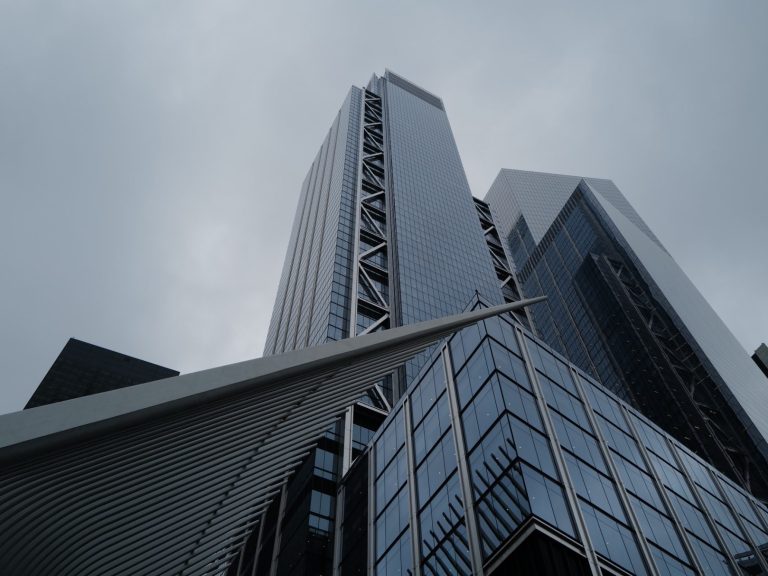 Moderne Wolkenkratzer unter bewölktem Himmel, Blick von unten nach oben.