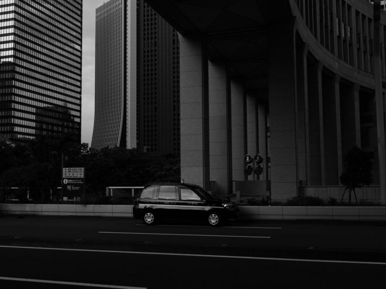 Schwarzes Auto parkt unter einem modernen Gebäude in der Stadt.